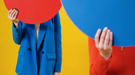 Anonymous trendy ladies covering faces with colorful sheets in studio